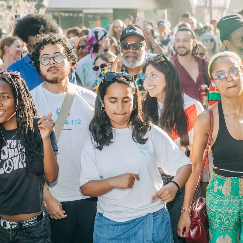 Young supporters in campaign T-shirts smiling together in the crowd.